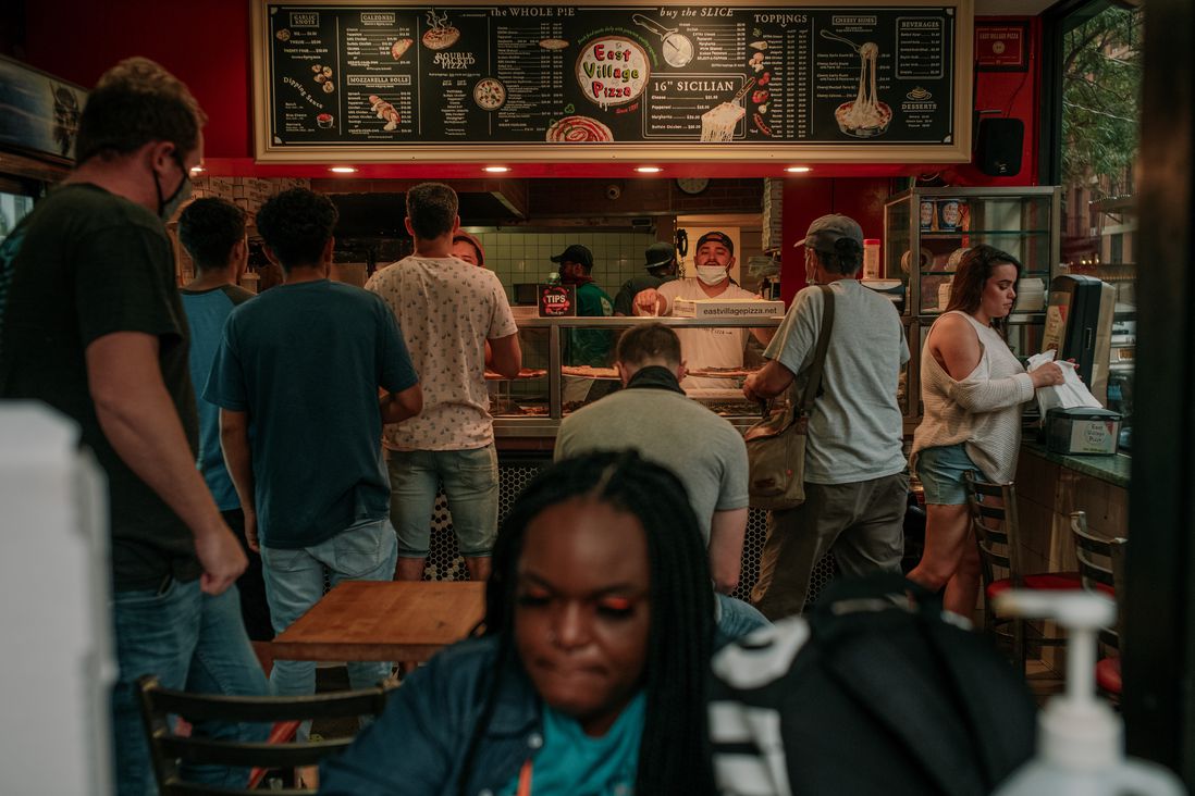 A photo of people waiting on line for pizza